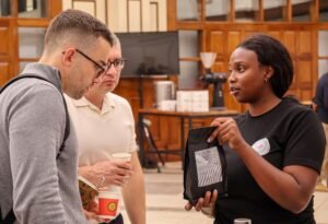 An EACMC exhibitor presenting packaged coffee to international visitors